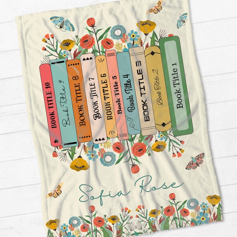 May include: A cream-colored fleece blanket with a stack of colorful books with floral accents and the text "Sofia Rose".