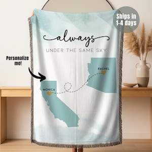 May include: A personalized throw blanket with a watercolor sky design. The text reads "always under the same sky." It features state outlines with locations marked, connected by a dotted line. The blanket has a fringed edge and the text "Personalize me!"