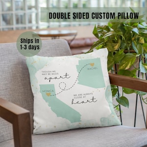 May include: A white throw pillow with a green watercolor map of the United States. The map shows two states connected by a dotted line with a heart at each end. The text "Though we may be miles apart, we are always close at heart" is printed on the pillow. The names "Rachel" and "Monica" are printed on the states.