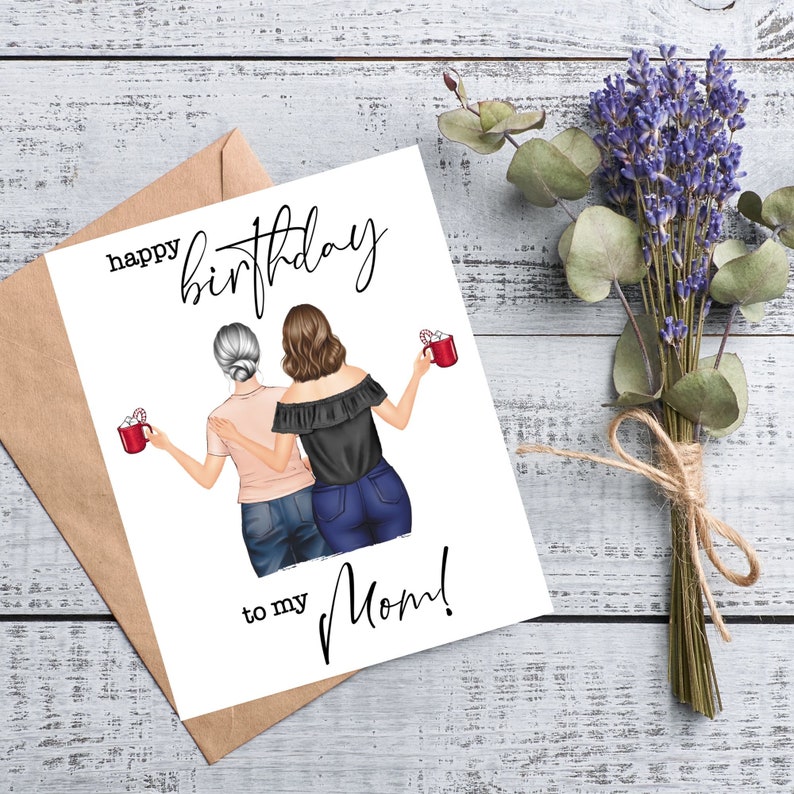 May include: A birthday card with the text "Happy Birthday to my Mom!" features an illustration of two women holding mugs. The card is next to a brown envelope and a bundle of lavender and eucalyptus tied with twine.