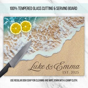 K&ouml;nnte beinhalten: Ein temperiertes Glas-Schneidebrett mit einer Strandszene mit blauem Wasser, wei&szlig;en Wellen und gelben Zitronen. Das Brett ist personalisiert mit dem Text "Luke & Emma EST. 2025".