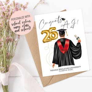 May include: A graduation card with the text "Congrats A.J.!" features a graduate in a black gown and red stole, holding a diploma. Gold balloon numbers "26" are included. The card is personalized with school colors, name, class, and school.