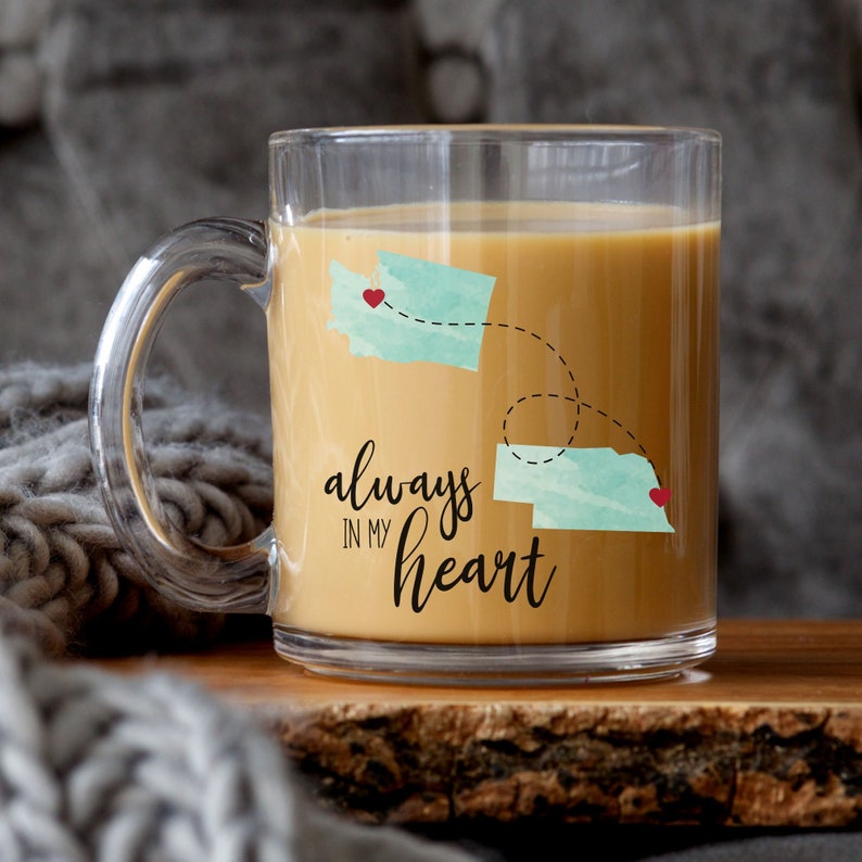 May include: Clear glass coffee mug with a design of two states connected by a dotted line and the text "always in my heart".