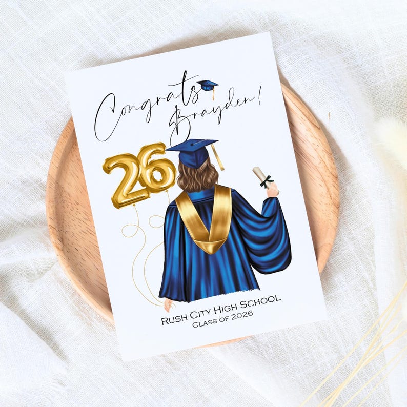 May include: A graduation card featuring an illustration of a graduate in a blue gown and gold stole, holding a diploma. Gold balloon numbers read "26". The card reads "Congrats Brayden!" and "Rush City High School Class of 2026".