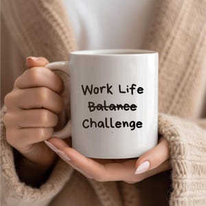 Op de afbeelding: Een witte keramische mok met zwarte handgeschreven tekst die "Work Life Balance Challenge" luidt.