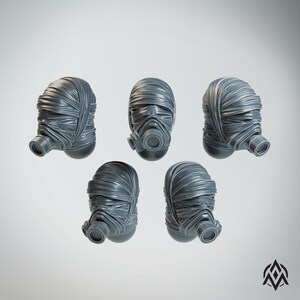 May include: A set of five grey miniature heads, each wrapped in textured bandages and featuring a prominent circular gas mask filter attached to the front. The heads are arranged in a cluster, displaying detailed folds and creases in the material.