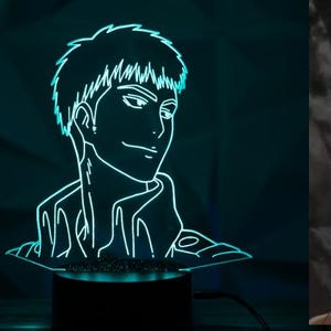 May include: A two-part image featuring a teal-colored LED light and a character illustration. The LED light depicts a male anime character with a smiling expression. The illustration shows the same character in a brown jacket.
