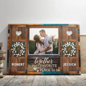 May include: A rustic wooden canvas print with a photo of a couple in a window frame. The text "together is our favorite place to be" is written below the photo. The names "Robert" and "Jessica" are written on either side of the text.