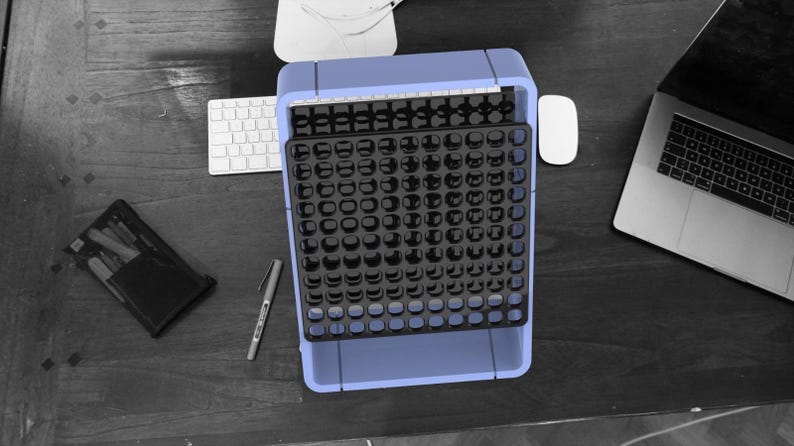 May include: A blue plastic organizer with a black gridded tray. The tray has many small compartments for holding small items.