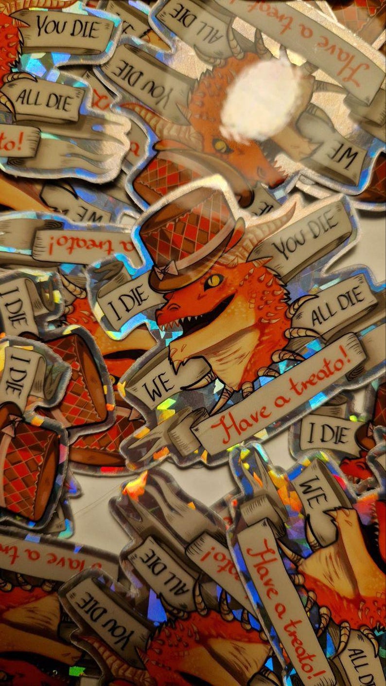 Może przedstawiać: Zbi&oacute;r holograficznych naklejek z kresk&oacute;wkowym smokiem w cylindrze trzymającym znak z napisem "Have a treato!" Naklejki zawierają r&oacute;wnież tekst "You Die", "All Die" i "I Die".