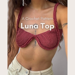 May include: A burgundy crochet Luna Top with a distinctive design. The top has a bra-like structure with thick straps and a detailed pattern. The image displays the text "A Crochet Pattern" and "Luna Top", along with "CROCHET - by orchid -."