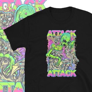 Può includere: T-shirt nera con una grafica colorata di un alieno che abbraccia una creatura simile a un gatto. La parola "ATTACK" è stampata sopra e sotto l'illustrazione in un carattere vibrante e multicolore. Il design è in stile fumetto.