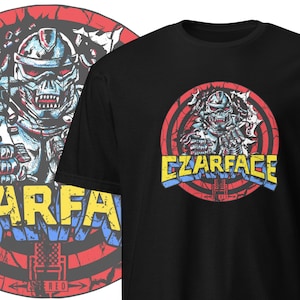 May include: Black t-shirt with a graphic of a robot wearing a helmet and holding a microphone. The robot is surrounded by a red, yellow, and blue circle with the text "CZARFACE" in a retro font.