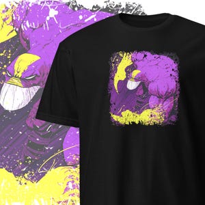 May include: A black t-shirt featuring a purple and yellow graphic of a muscular figure wearing a mask. The figure is in a fighting pose with a splatter effect around it.
