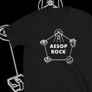 May include: Black t-shirt with a white graphic design of a five-pointed star with an eye, a skull, a heart, a stack of money, and a moon. The text "AESOP ROCK" is inside the star.