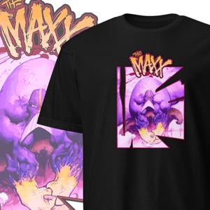 Pode incluir: Camiseta preta com um gráfico roxo e rosa de um personagem do gibi "The Maxx". O personagem está usando uma máscara e tem um corpo grande e musculoso. O texto "The Maxx" está escrito em uma fonte estilizada acima do personagem.