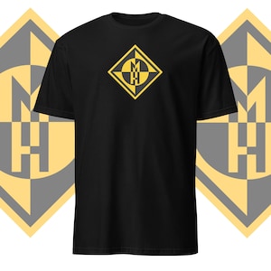 Puede incluir: Camiseta negra con un logotipo amarillo en forma de diamante que presenta las letras "MH" en un círculo con un diseño de brújula.