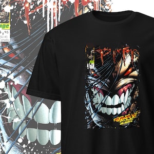 May include: Black t-shirt featuring a graphic print of a comic book character with sharp teeth and red eyes. The character's name is "Spawn" and part of the comic book cover is visible.