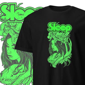 Peut inclure: T-shirt noir avec un imprimé graphique vert d'une femme avec des fleurs dans les cheveux et un crâne avec des bois. Le texte "Sleep" est imprimé en vert au-dessus du graphique.