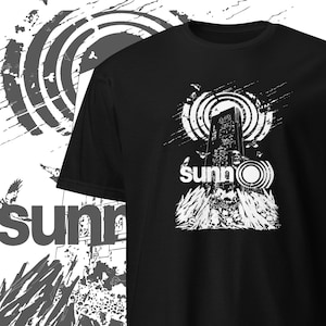 Puede incluir: Camiseta negra con un diseño gráfico blanco de un edificio alto con un círculo y la palabra "sunno" impresa debajo.