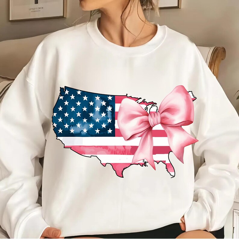 May include: White sweatshirt featuring a graphic of the United States outline with an American flag and a pink bow.