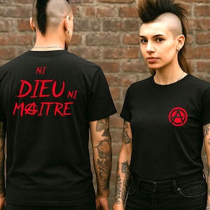 Peut inclure: T-shirts noirs avec des graphiques rouges. L'un affiche le texte "NI DIEU NI MAITRE" au dos, et l'autre présente un symbole d'anarchie sur le devant. Les deux t-shirts sont à manches courtes.