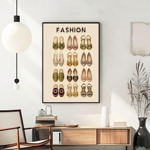May include: A framed wall art print on a cream background featuring the word FASHION at the top in brown letters. Below the text are four rows of illustrated women's footwear, including various styles of flats, loafers, and sandals in diverse colors.