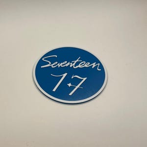 May include: A blue and white round sticker with the text "Seventeen 17" in white.