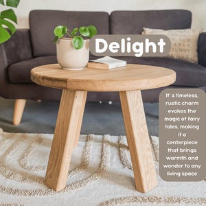 May include: A round wooden table with three legs, sitting on a cream-colored rug with a pattern of arches. The table is in front of a brown couch with a throw pillow that says "YUMMY". The table has a plant in a white pot on top of it. The text "Delight" is written in a white box above the table.