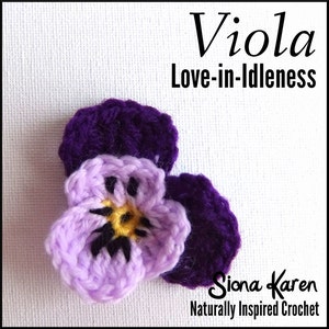 May include: A crocheted violet flower with a light purple and yellow center, and dark purple petals. The text "Viola Love-in-Idleness" is above the flower, and "Siona Karen Naturally Inspired Crochet" is below.