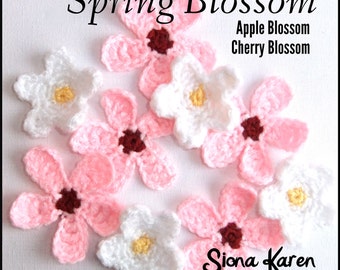 May include: A collection of crocheted flower embellishments in pink and white. The flowers are labelled "Spring Blossom", "Apple Blossom", and "Cherry Blossom". The flowers are made by Siona Karen, Naturally Inspired Crochet.