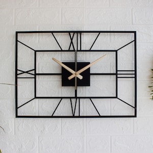 May include: A rectangular black metal wall clock with Roman numerals and light-coloured wooden clock hands. The clock is mounted on a white brick wall, creating a modern, minimalist aesthetic.
