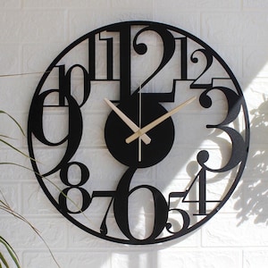 May include: Black metal wall clock with large, bold numbers. The clock has a black face and gold hands.