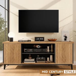 May include: A mid-century style TV stand with a large black screen above. The stand has two wooden doors with a geometric design, and open shelving for electronics and decor. The stand is made of wood and metal.