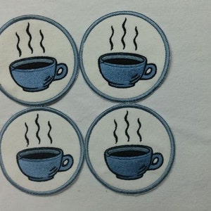 May include: Four white round coasters with blue coffee cups and steam coming from the cups.