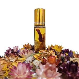 May include: A clear glass roll-on bottle with a gold cap, filled with a yellow liquid and dried flowers. The bottle is surrounded by a bed of colorful dried flowers in shades of pink, yellow, orange, and purple.