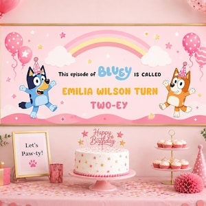Op de afbeelding: Een roze verjaardagsfeestje met een banner met Bluey-personages, ballonnen en een regenboog. De banner luidt "This episode of Bluey is called Emilia Wilson Turn Two-ey." Een taart, cupcakes en cadeaus staan op tafel.