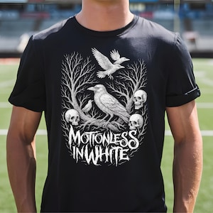May include: Black t-shirt featuring a detailed white graphic. The design includes a crow perched on a branch, skulls, and the text "MOTIONLESS IN WHITE". The artwork has a gothic, dark aesthetic.