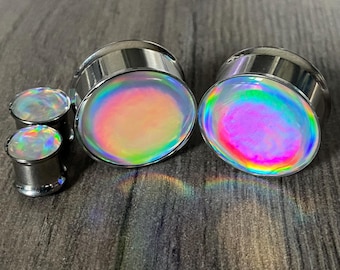 May include: Set of four iridescent ear gauges, two large and two small, with silver metal rings. The gauges have a rainbow effect.