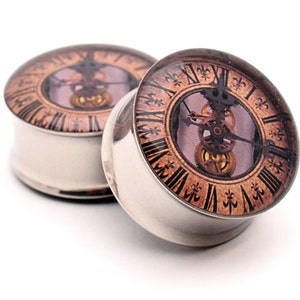 May include: A pair of stainless steel ear gauges with a clock face design. The clock face is brown with gold gears and a white background. The gauges are 1/2 inch in diameter.