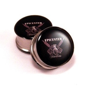 May include: Pair of black ear gauges with a silver metal rim. The gauges feature a white logo that says "Epicenter Studios" with a graphic of crossed swords and a skull.