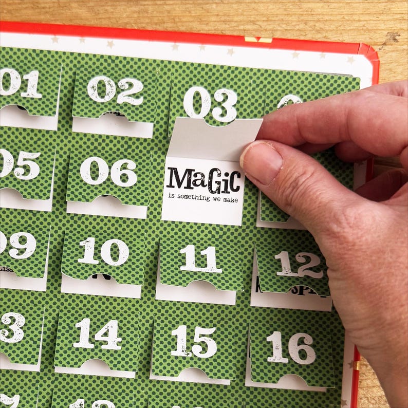 Puede incluir: Un calendario de adviento verde y blanco con solapas numeradas. La solapa del d&iacute;a 3 est&aacute; abierta, revelando una tarjeta blanca con el texto "MaGic is something we make".