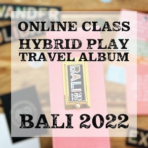 Pode incluir: Um álbum de viagem rosa com o texto "ONLINE CLASS HYBRID PLAY TRAVEL ALBUM" e "BALI 2022". O álbum tem um fecho de metal dourado com a palavra "BALI" e o ano "22". O fundo é uma superfície de madeira.