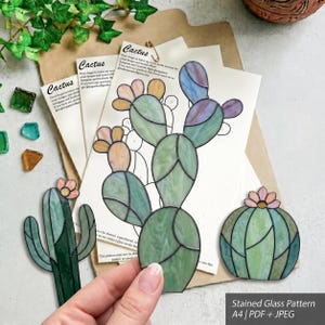 Op de afbeelding: Een set glas-in-loodpatronen met drie verschillende cactusontwerpen op A4-papier. De patronen bevatten een hoge schijfcactus, een slanke zuilcactus en een ronde bolcactus, allemaal met pastelgroene, roze en blauwe glazen segmenten.