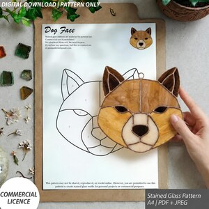 May include: A digital download stained glass pattern for a dog face, featuring a line drawing on A4 paper and a finished tan and cream glass piece with dark solder lines. The text reads Dog Face, Digital Download, and Pattern Only.