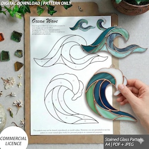 Può includere: Un modello per vetrate artistiche in download digitale intitolato Ocean Wave, che presenta due sagome in bianco e nero con sezioni numerate e due ornamenti a forma di onda in vetro finiti, nei toni del blu, turchese e bianco con bordi in rame.