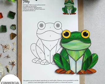 Könnte beinhalten: Ein Buntglas-Muster für einen Frosch, bestehend aus einer nummerierten Strichzeichnung auf weißem Papier und einem fertigen grünen Glasfrosch mit großen gelben Augen. Das Dokument enthält Text zu sozialen Medien und kommerziellen Lizenzen.