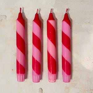 完璧に不完全な4つの赤とピンクの螺旋状のストライプの手で浸したカラフルなキャンドル