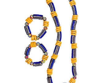 Puede incluir: Un conjunto de joyas de cuentas azules y amarillas, que incluye un collar y dos pulseras. El collar tiene una cuenta azul más grande en la parte inferior.