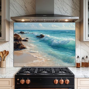 Puede incluir: Un protector contra salpicaduras de cocina con una vibrante escena oceánica. La obra de arte representa una playa arenosa, agua turquesa y olas rompiendo bajo un cielo azul con nubes blancas. Rocas marrones bordean la costa.
